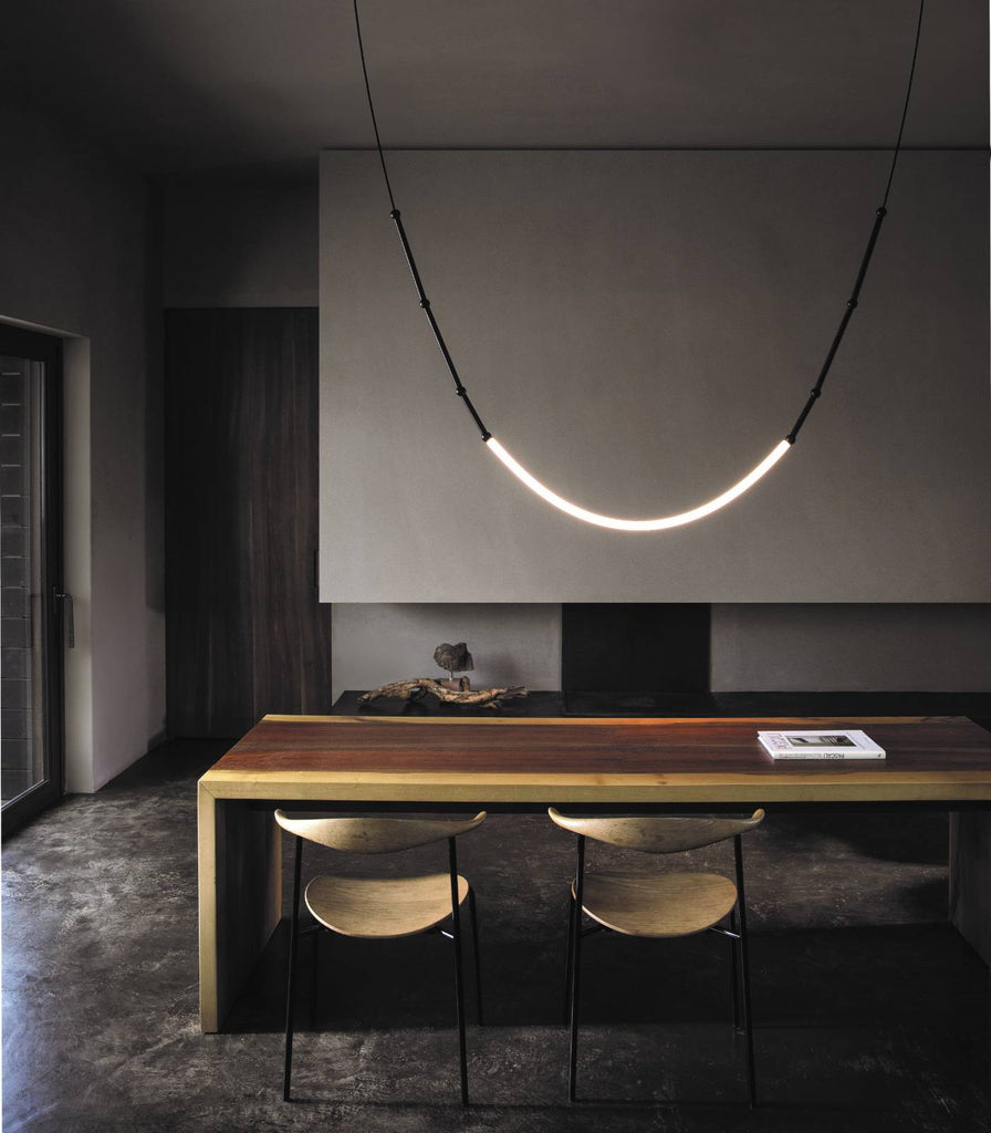 Karman Leda Curve Pendant Light hanging over dining table