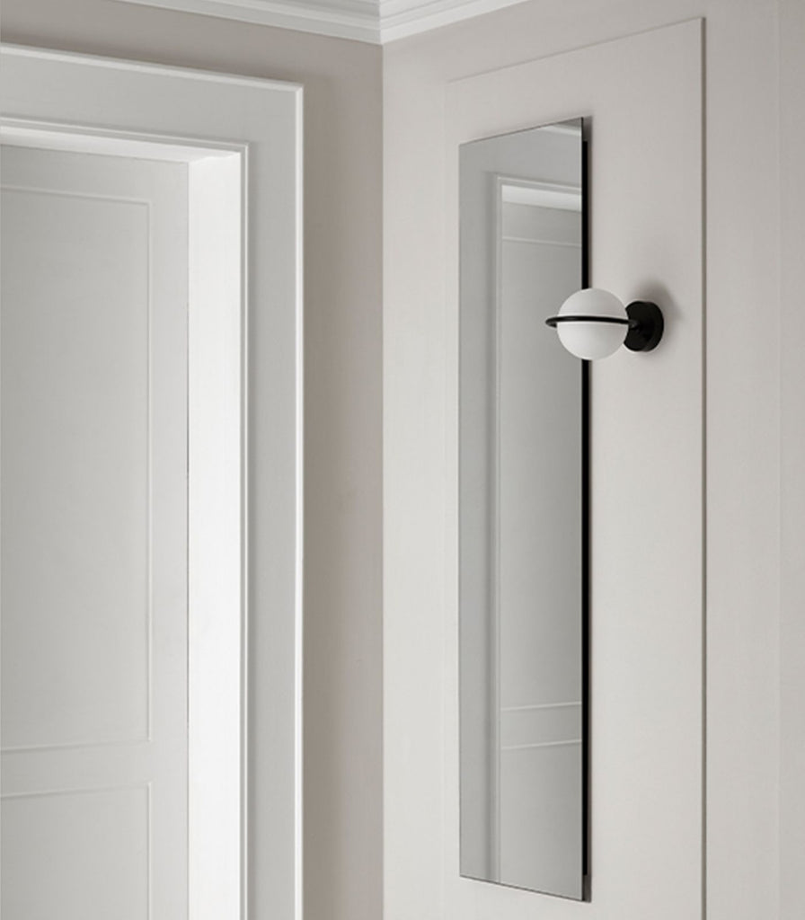 Aromas Abbacus Wall Light in Matte Black placed beside a mirror 