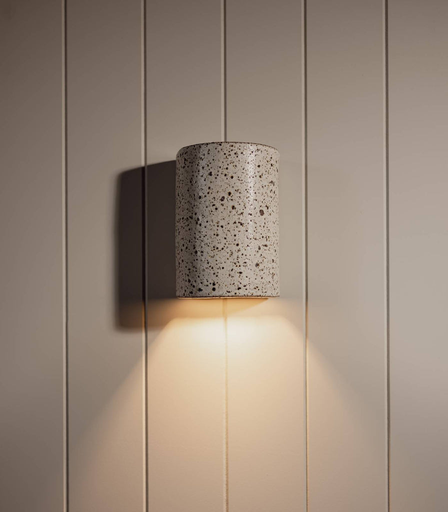 We Ponder Dusk Short Outdoor Wall Light in Fleck/Eggshell White turned on 